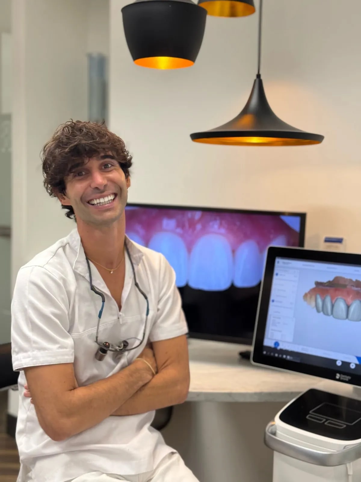 Dr. Victor Masip in the studio, beside an intraoral photograph and a CAD smile design on screen.